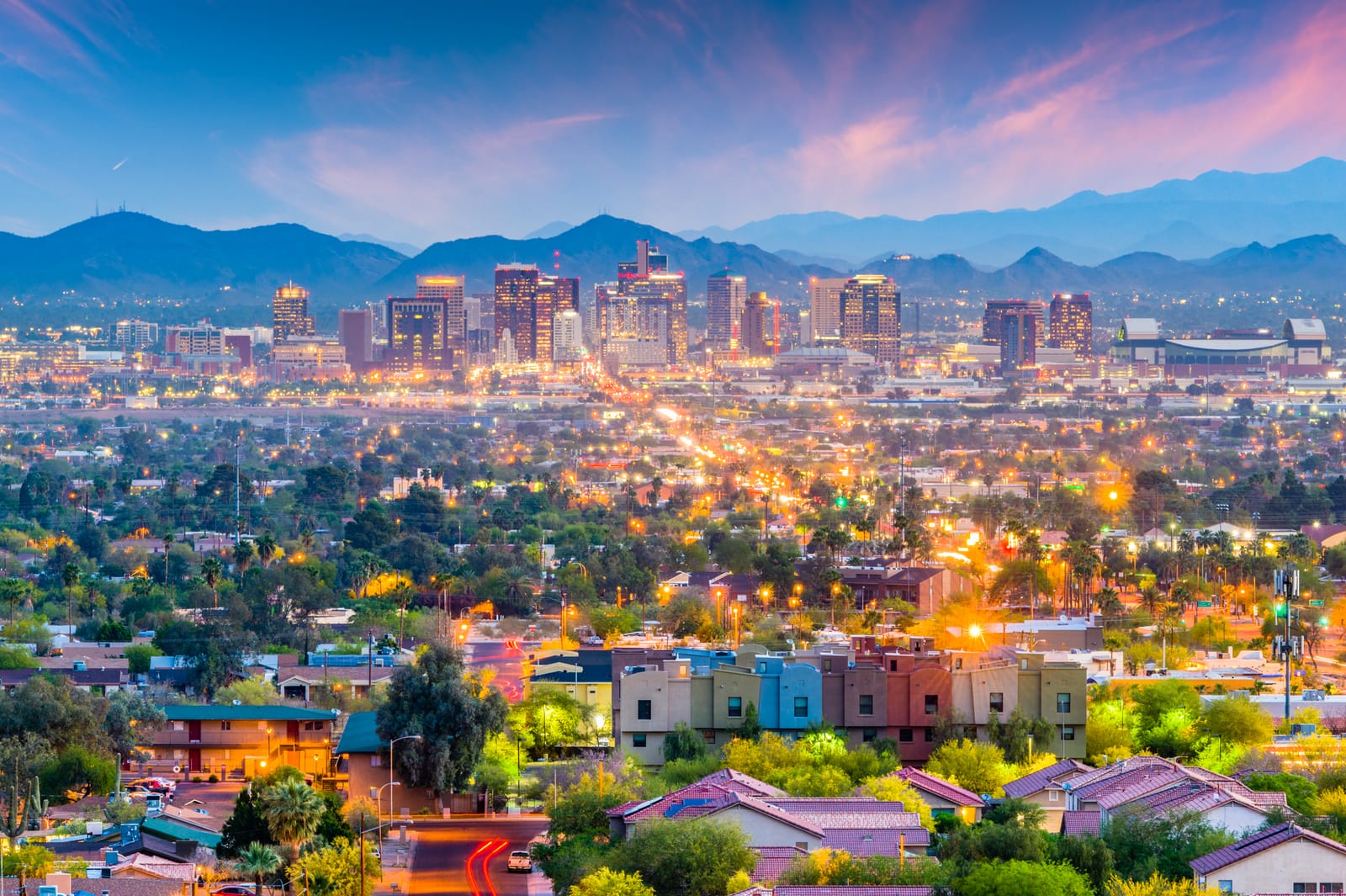Downtown Phoenix towers at dusk with mountains behind and colorful low-rise homes in the foreground
